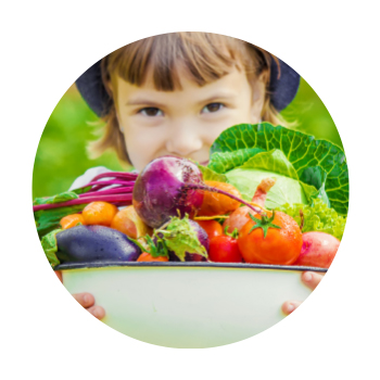 Child holding basket of vegetables