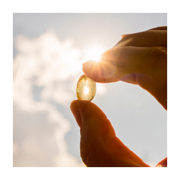 Image of a person holding a vitamin D capsule up to the sun